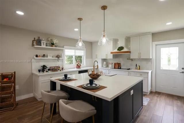 a kitchen with a sink a stove a refrigerator and white cabinets with wooden floor