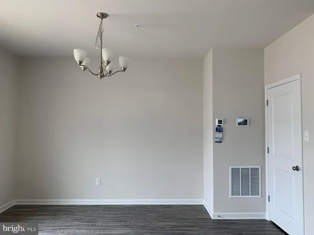 a view of an empty room with wooden floor and chandelier