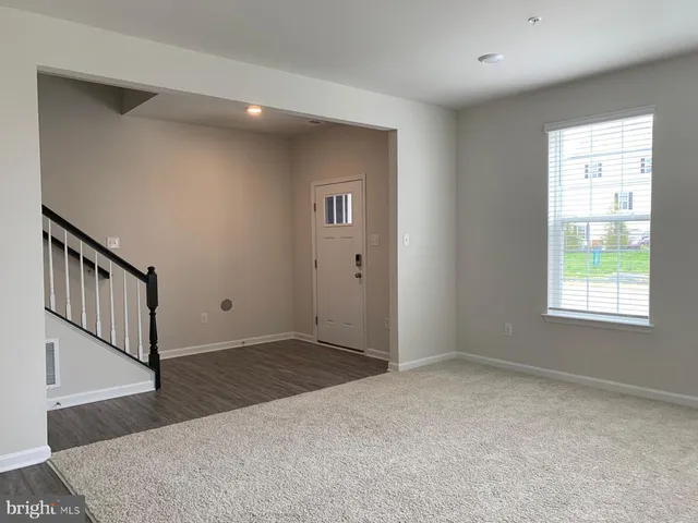 a view of an empty room with window and stairs