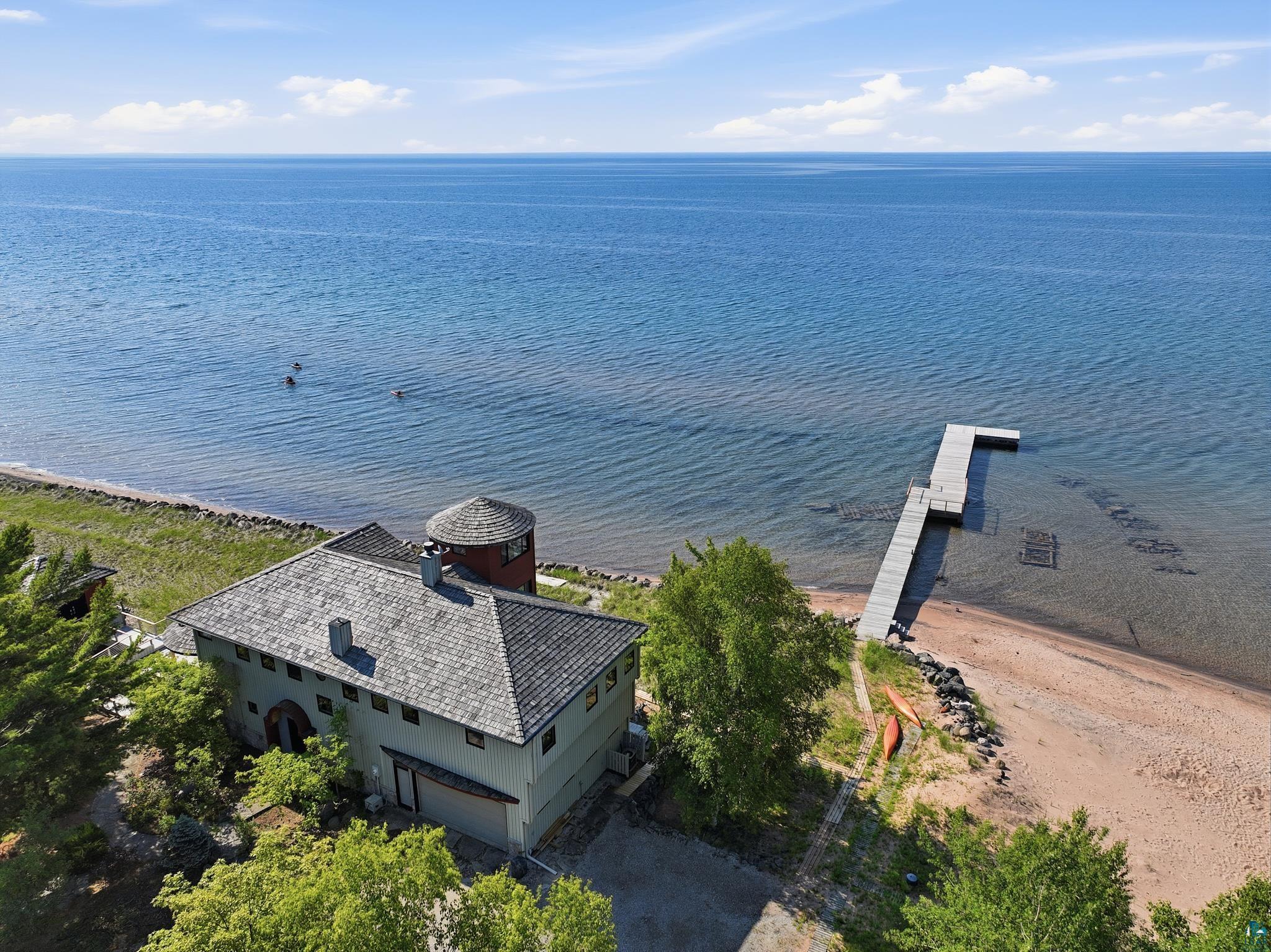3705 Big Bay Road La Pointe, WI 54850 - Photo 4 of 56 Waterfront property featuring a private dock, sandy beach, and a stucco exterior with a distinctive turret
