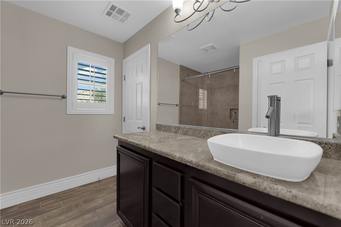 646 Monument Point Street Henderson, NV 89002 - Photo 26 of 44 Elegant dark cabinetry and a sleek vessel sink elevate this naturally illuminated bathroom.