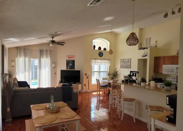 a living room with furniture kitchen view and a chandelier