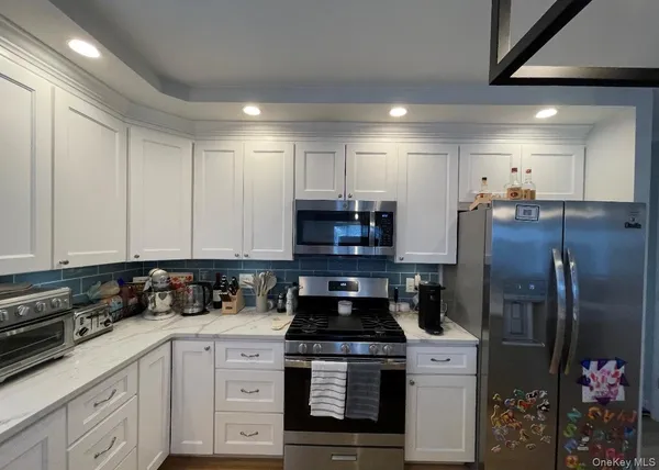 a kitchen with stainless steel appliances granite countertop a stove a refrigerator and a white cabinets