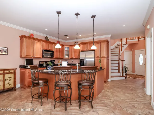 a kitchen with stainless steel appliances kitchen island granite countertop a refrigerator a stove top oven with a dining table and chairs with wooden floor