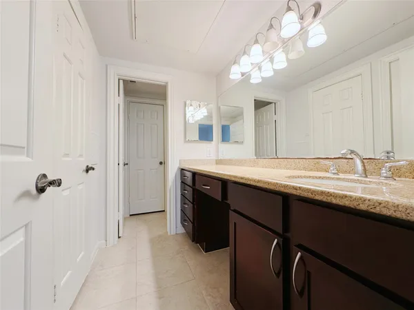 a bathroom with a granite countertop sink a light fixture and a mirror