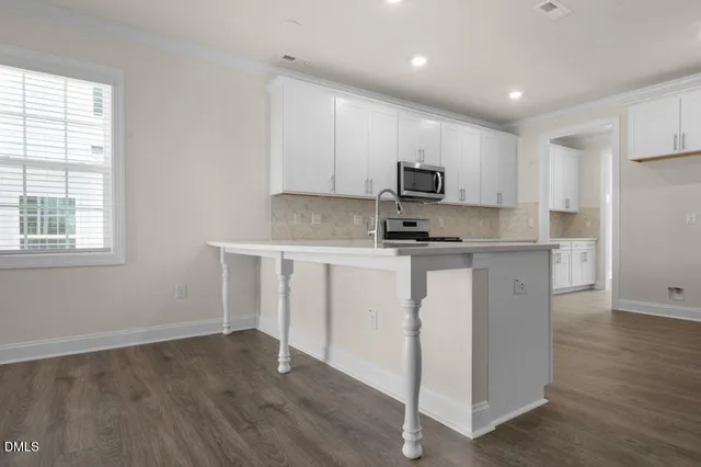 a kitchen with kitchen island white cabinets and black appliances