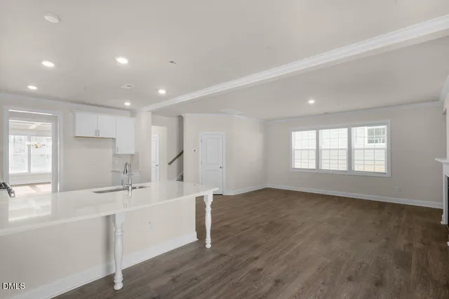 a large white kitchen with a sink wooden floor and a window
