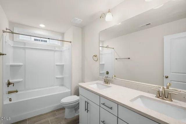 a bathroom with a sink a toilet a mirror a bathtub and shower