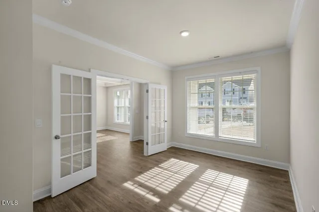 a view of an empty room with wooden floor and windows