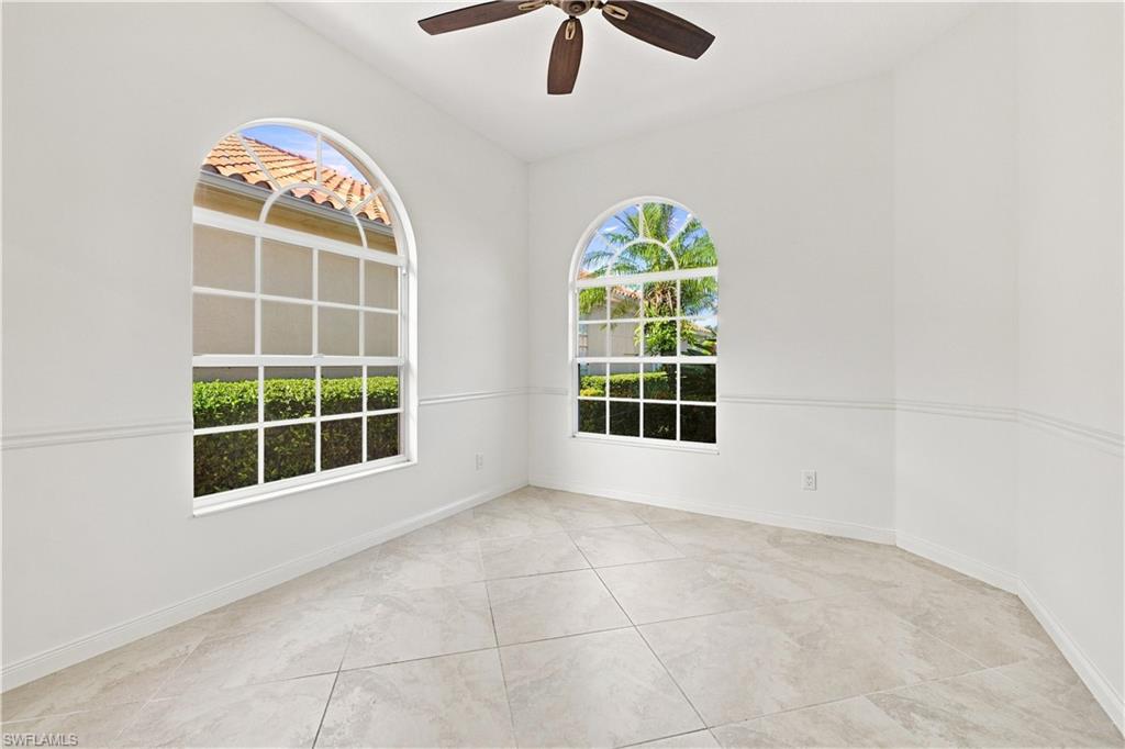4470 Novato Court Naples, FL 34109 - Photo 14 of 33 Arched windows with grid patterns, ceiling fan with dark wood-finish blades, light-toned tile flooring, and decorative wall molding