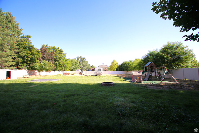 1612 East 450 South Springville, UT 84663 - Photo 4 of 48 Expansive backyard featuring a large green space, privacy fencing, mature trees, and a built-in fire pit