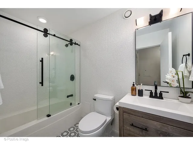 a bathroom with a granite countertop sink toilet a mirror and shower