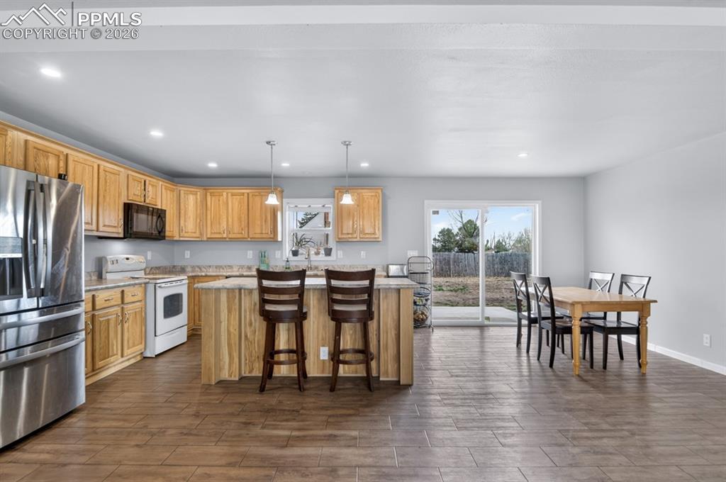 736 Indiana Avenue Limon, CO 80828 - Photo 16 of 37 a kitchen with stainless steel appliances granite countertop a stove top oven a sink dishwasher a dining table and chairs with wooden floor