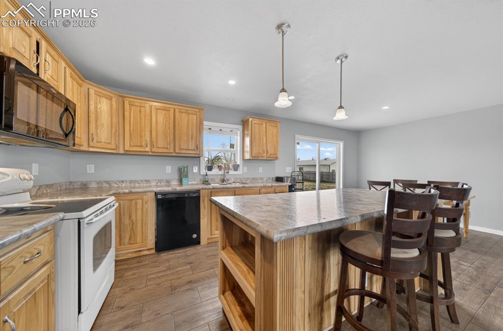 736 Indiana Avenue Limon, CO 80828 - Photo 18 of 37 a kitchen with a stove a sink a kitchen island with chairs and wooden cabinets