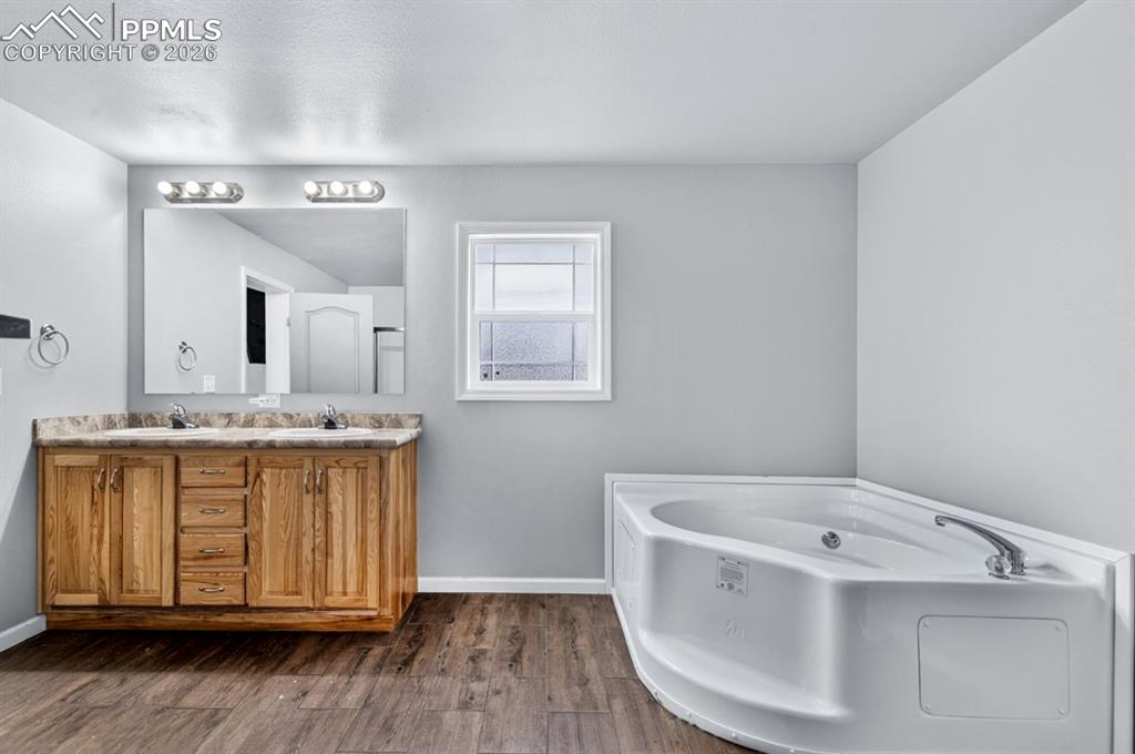 736 Indiana Avenue Limon, CO 80828 - Photo 23 of 37 a bathroom with a granite countertop bathtub a sink and wooden floor