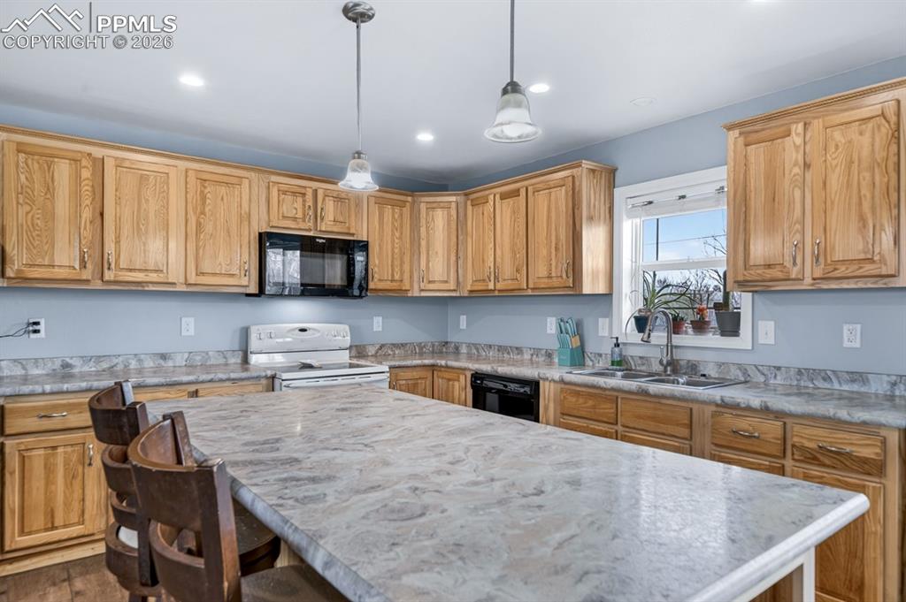 736 Indiana Avenue Limon, CO 80828 - Photo 10 of 37 a kitchen with granite countertop wooden cabinets a stove a sink a dining table and chairs