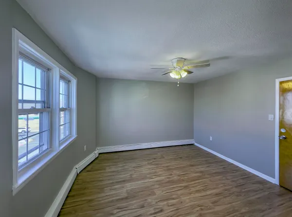 a view of an empty room with wooden floor and a window