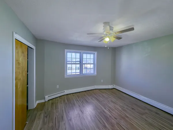 a view of an empty room with window and wooden floor