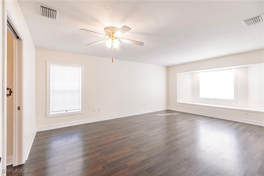 27425 Jones Loop Road Punta Gorda, FL 33982 - Photo 24 of 46 an empty room with wooden floor chandelier fan and windows