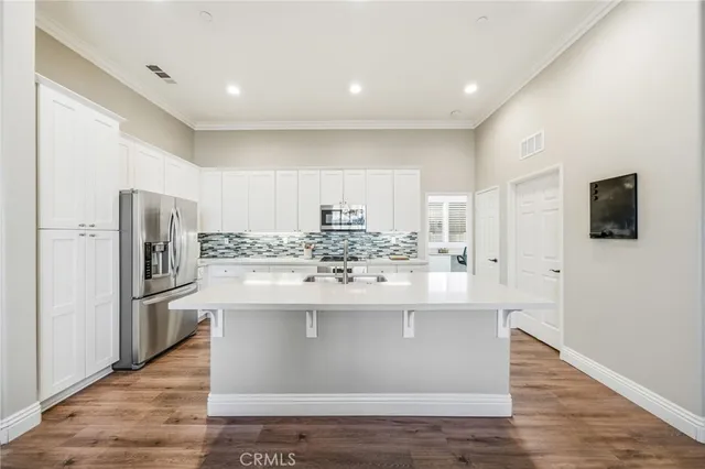 a view of a kitchen with wooden floor and stainless steel appliances