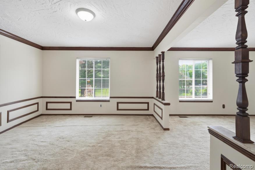 7020 Rattalee Lake Road Clarkston, MI 48348 - Photo 13 of 47 Open interior space featuring light-toned carpeting and contrasting dark wood trim