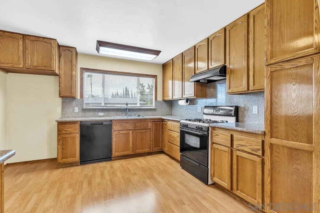9540 Abbeyfield Road Santee, CA 92071 - Photo 9 of 35 a kitchen with stainless steel appliances granite countertop a stove a sink dishwasher a refrigerator and cabinets with wooden floor