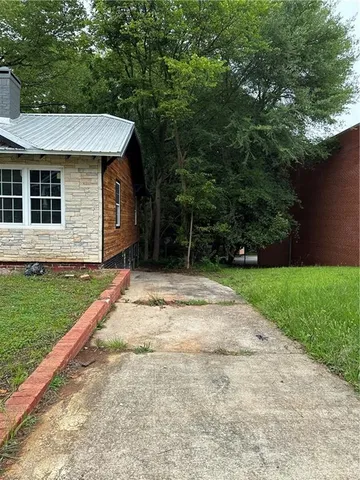 a view of a house with a yard plants and large tree