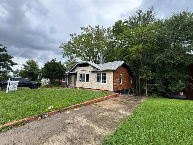 a view of a house with a yard and large tree