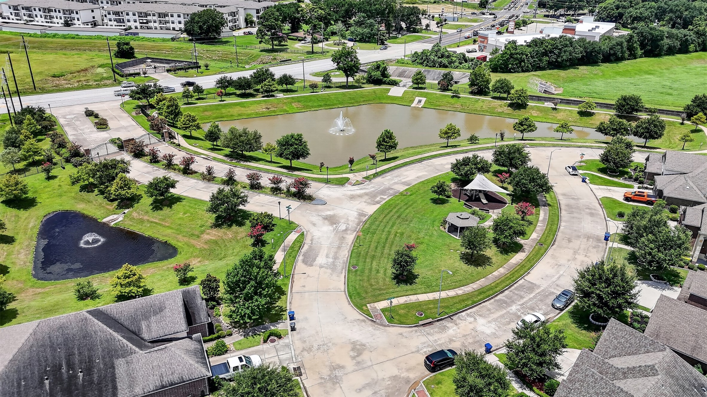 6234 Avon Landing Lane Spring, TX 77379 - Photo 40 of 49 A drone shot showing the entrance of the community, which is gated, with a spectacular fountain, on both sides of the street, within the pond as you approach the entrance which has a playground and shaded areas to sit and relax.