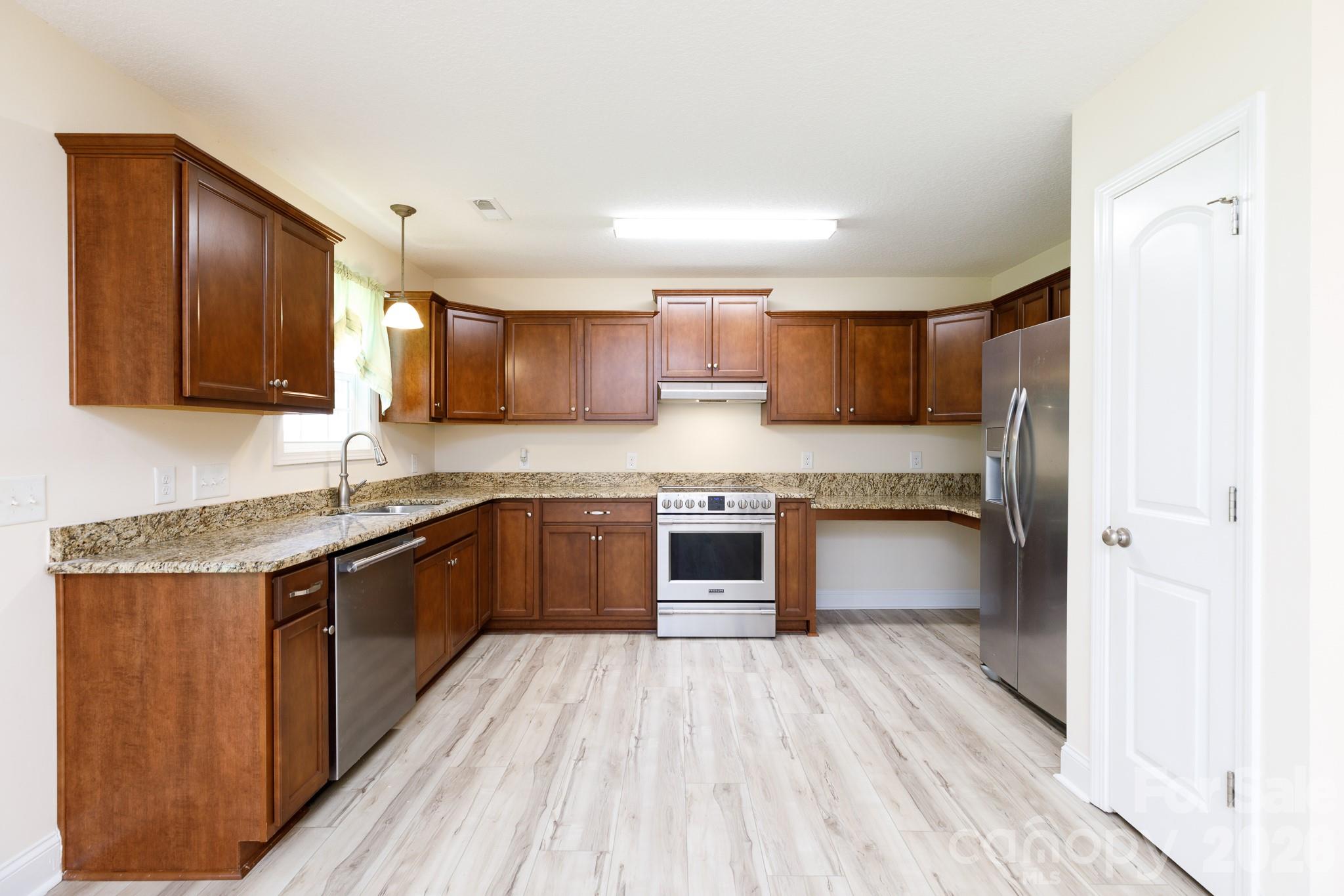 3692 Armstrong Ford Road Rock Hill, SC 29730 - Photo 10 of 30 a kitchen with stainless steel appliances granite countertop wooden cabinets a stove top oven a sink and dishwasher with wooden floor