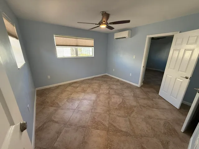 an empty room with windows and fan