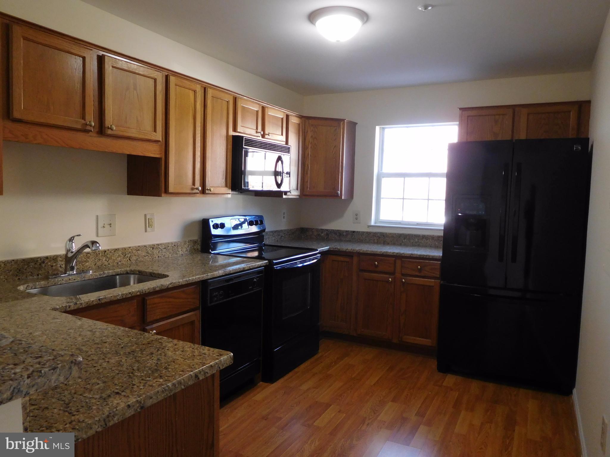 304 Ridgepoint Place, Unit 14 Gaithersburg, MD 20878 - Photo 6 of 25 a kitchen with granite countertop stainless steel appliances a sink stove refrigerator and a window
