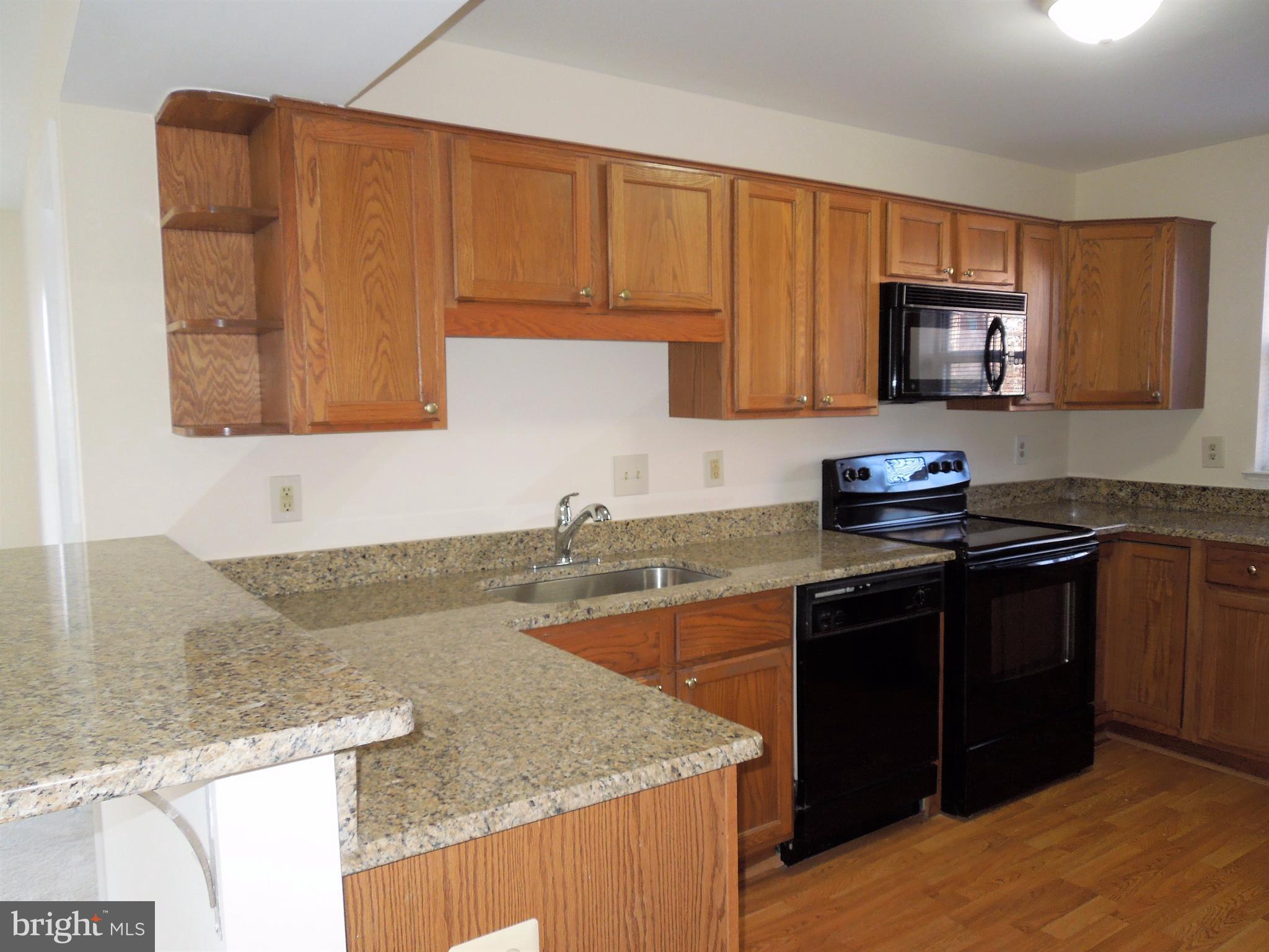 304 Ridgepoint Place, Unit 14 Gaithersburg, MD 20878 - Photo 7 of 25 a kitchen with granite countertop a sink dishwasher stove and cabinets with wooden floor