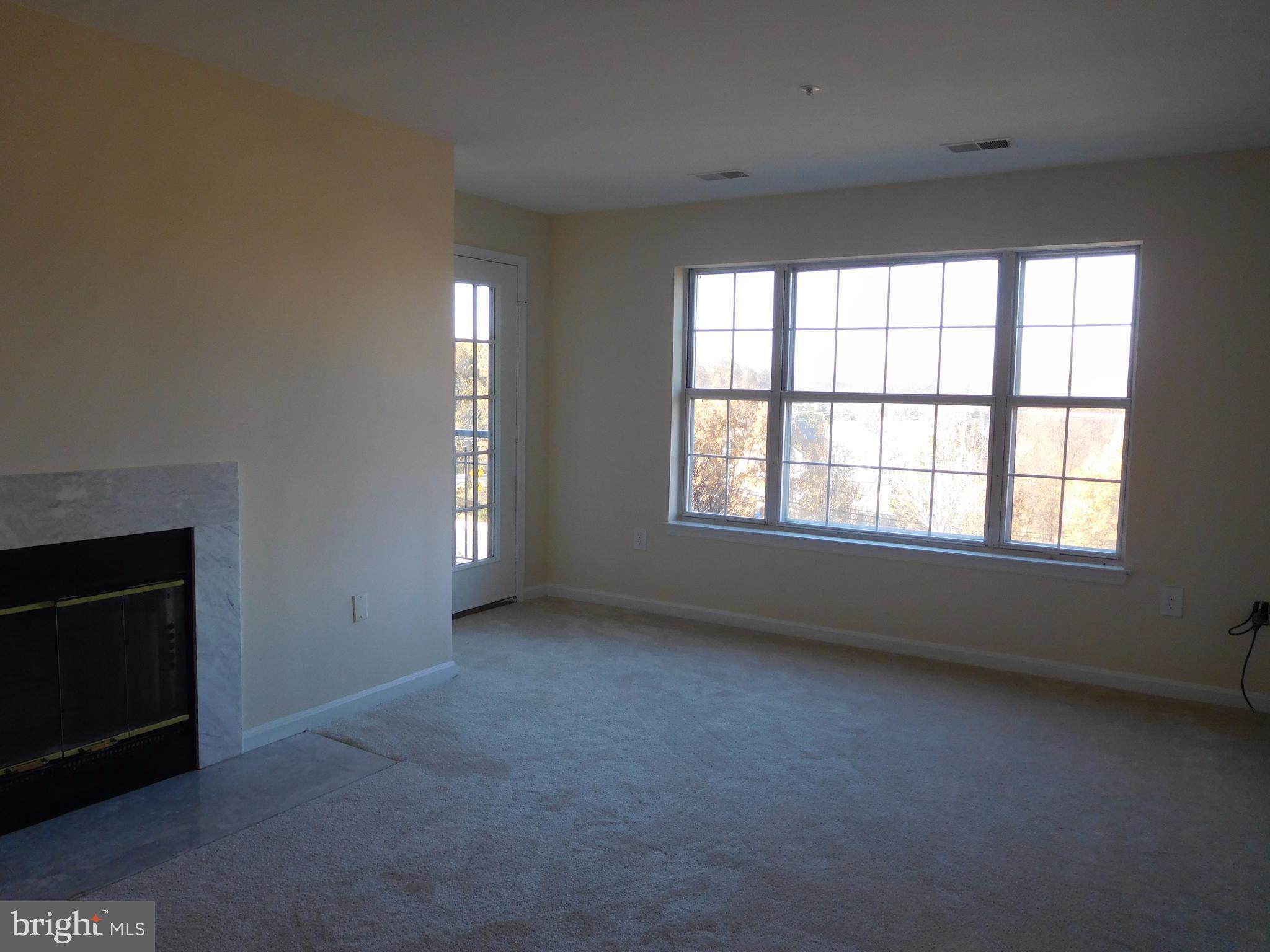 304 Ridgepoint Place, Unit 14 Gaithersburg, MD 20878 - Photo 8 of 25 an empty room with windows and fireplace