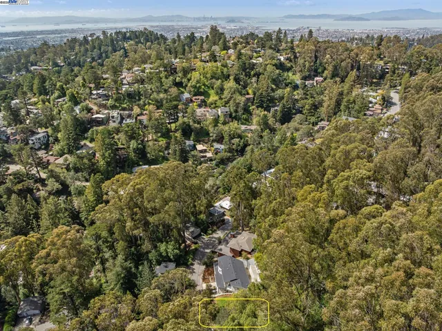 an aerial view of residential house with outdoor space and trees all around