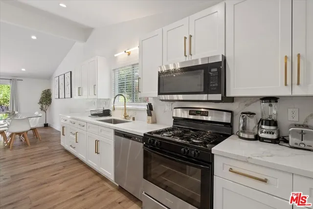 a kitchen with stainless steel appliances granite countertop a stove a sink and a microwave