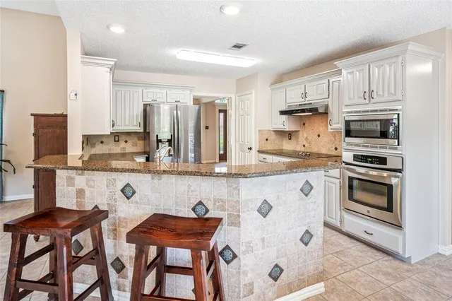 a kitchen with stainless steel appliances granite countertop a stove a sink and a refrigerator