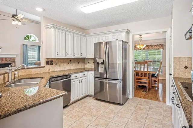 a kitchen with granite countertop a refrigerator oven a sink a dining table and chairs