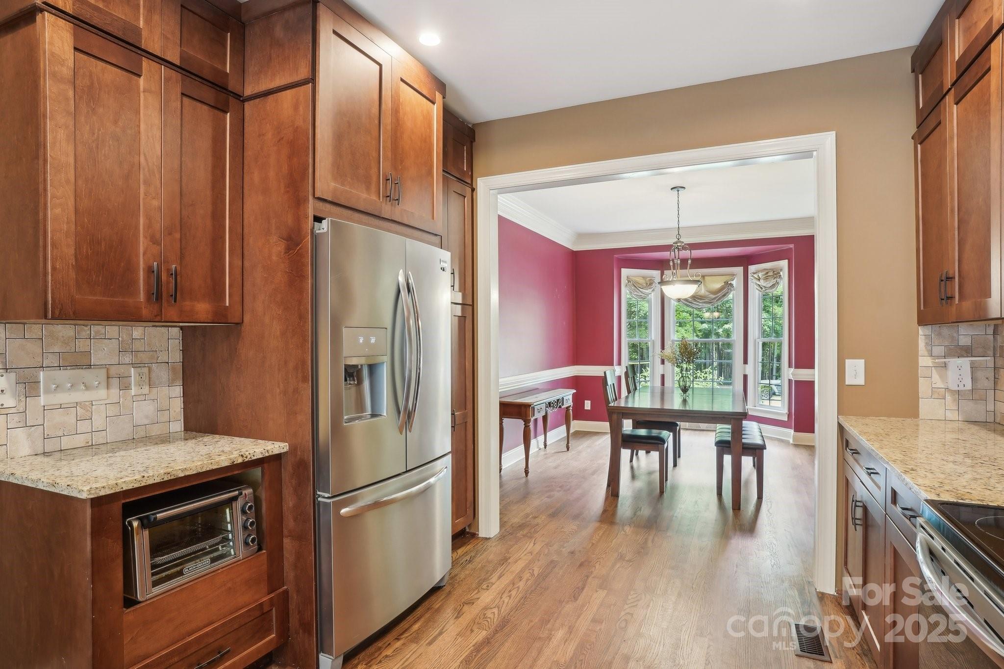134 Lake Spring Loop Mooresville, NC 28117 - Photo 11 of 36 a kitchen with stainless steel appliances granite countertop a refrigerator a stove and a dining table with wooden floor