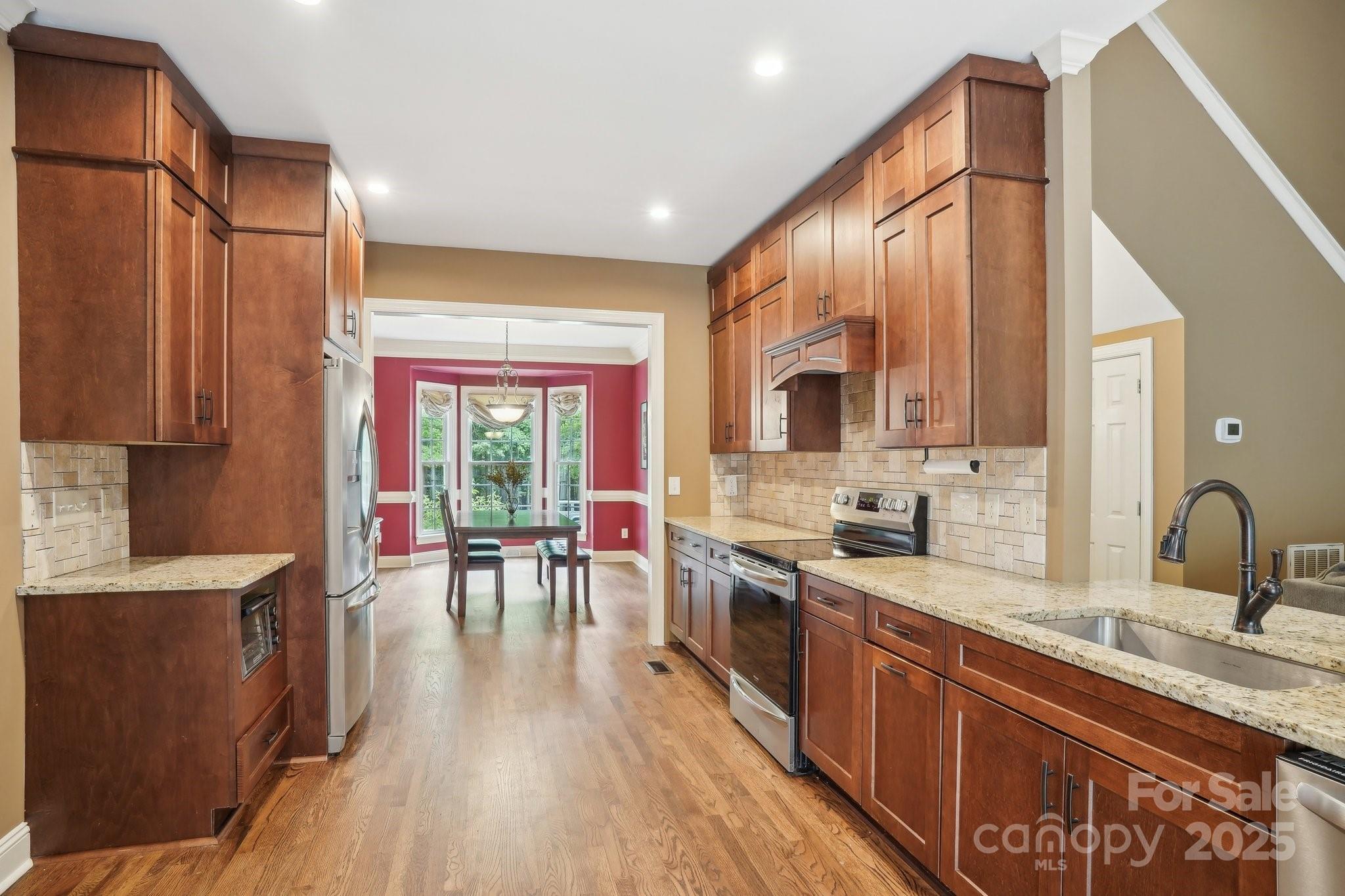 134 Lake Spring Loop Mooresville, NC 28117 - Photo 10 of 36 a kitchen with stainless steel appliances granite countertop a sink stove and wooden cabinets