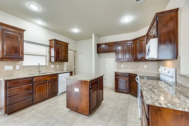 a spacious bathroom with a granite countertop sink a mirror and a bathtub