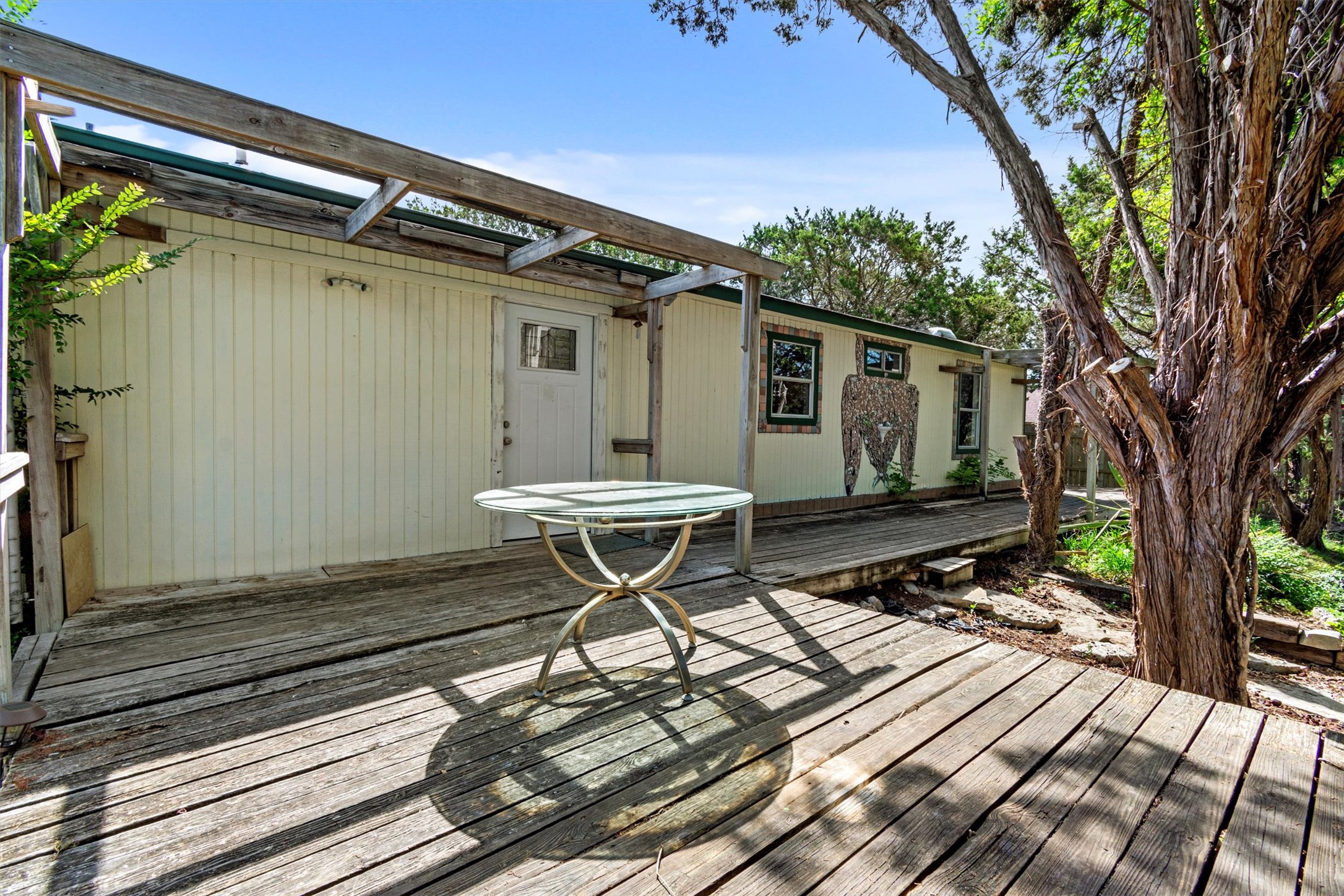 6 El Sol Road Wimberley, TX 78676 - Photo 16 of 20 A spacious wooden deck provides ample outdoor living space, nestled among mature trees.