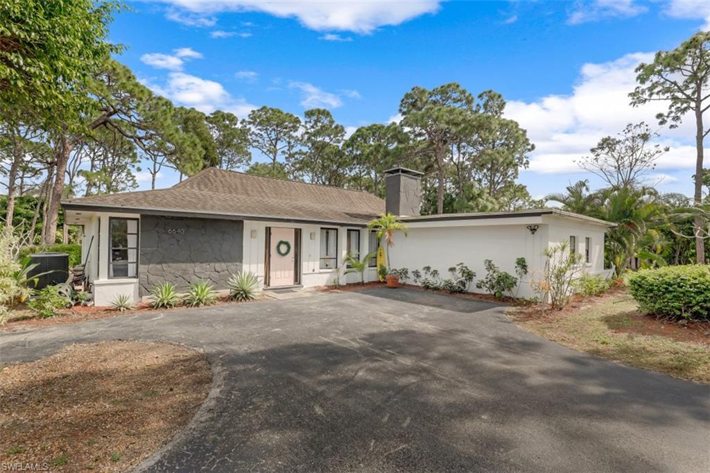 6640 Trail Boulevard Naples, FL 34108 - Photo 2 of 25 a front view of a house with a garden and yard