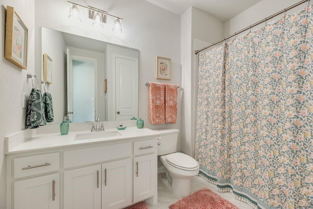 227 Buffalo Boulevard Rhome, TX 76078 - Photo 26 of 39 a bathroom with a toilet a sink and a large mirror