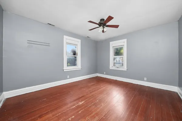 a view of a big room with wooden floor and windows