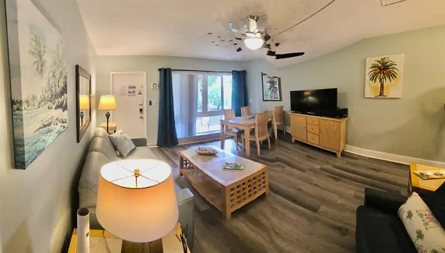 a living room with furniture a flat screen tv and kitchen view