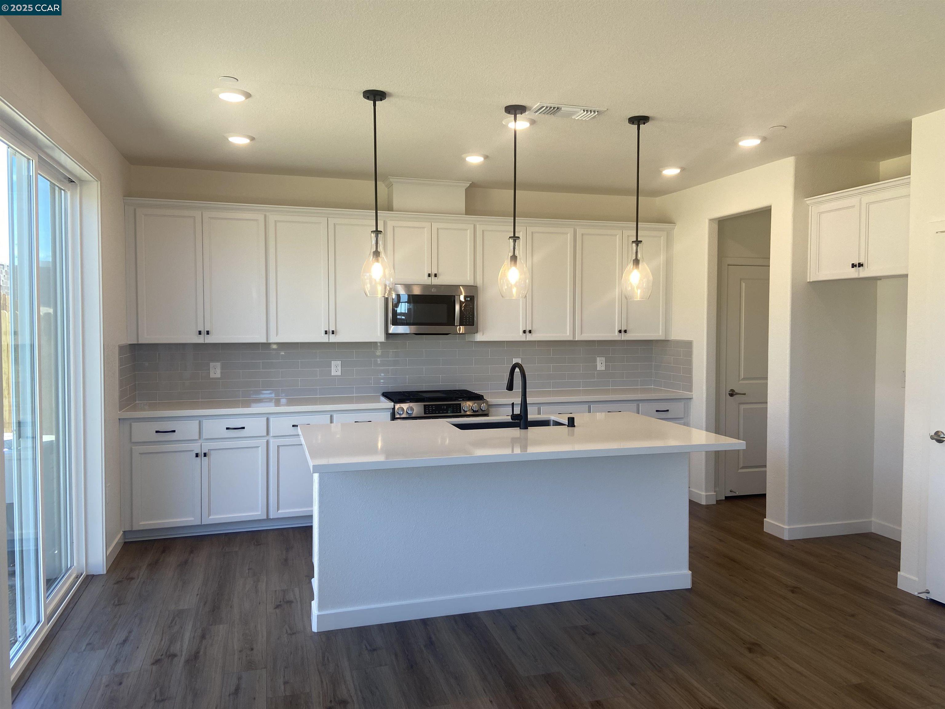 4786 Cantrell Drive Folsom, CA 95630 - Photo 14 of 30 a kitchen with kitchen island a sink a stove a refrigerator and white cabinets
