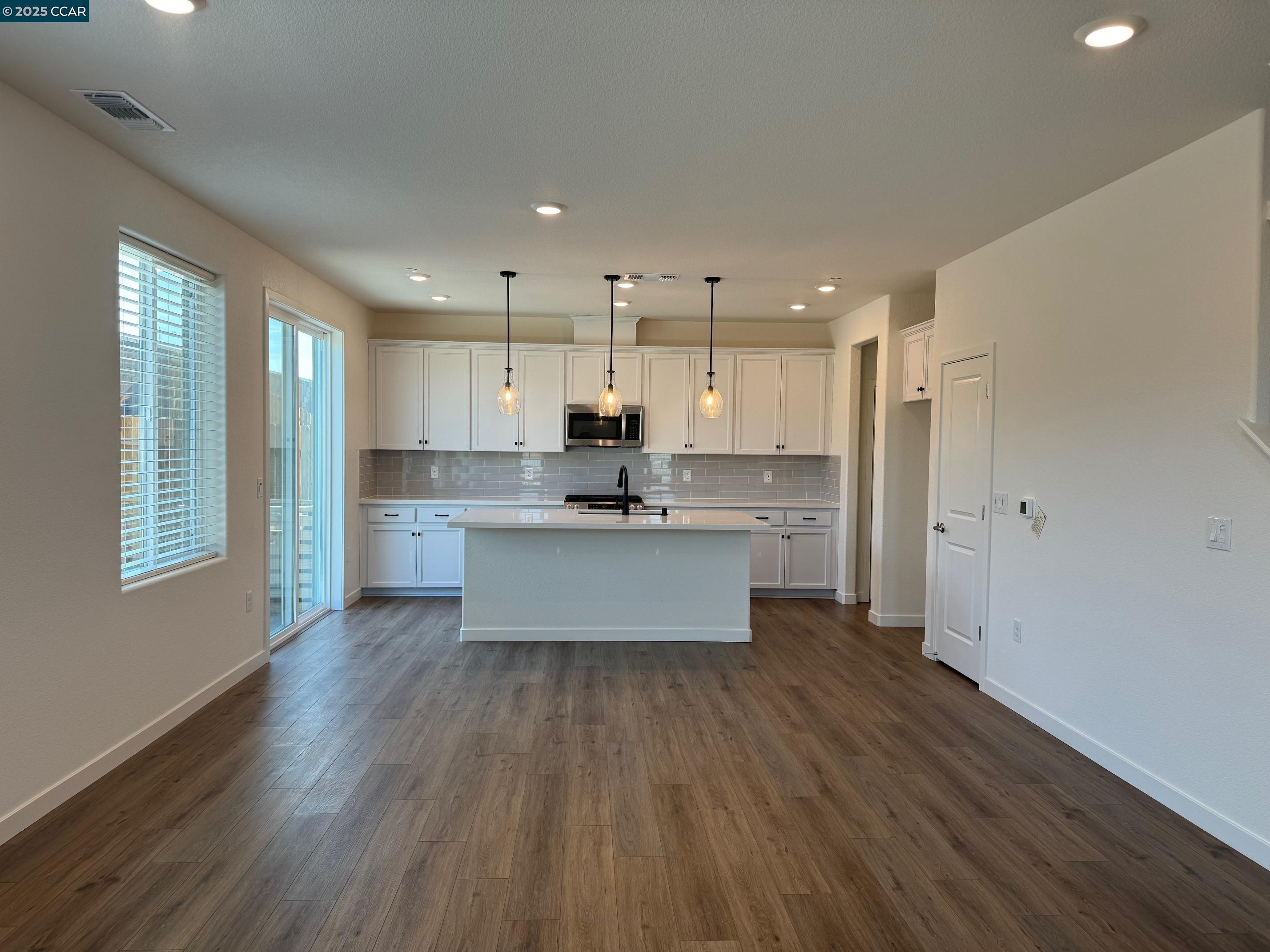 4786 Cantrell Drive Folsom, CA 95630 - Photo 7 of 30 a large kitchen with a center island wooden floor stainless steel appliances and a window