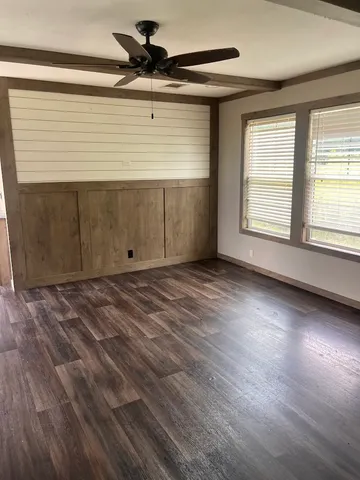 an empty room with wooden floor and windows