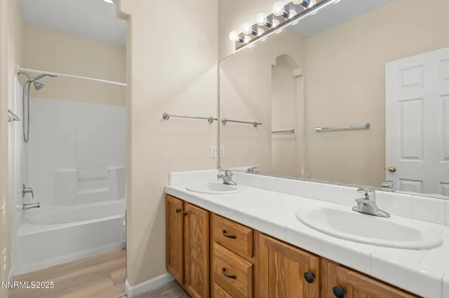 a bathroom with a sink double vanity granite tub shower and a mirror